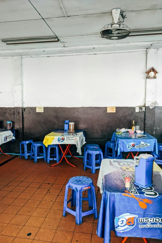 blue tables and chairs sitting under a tiled ceiling