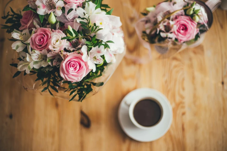 a table with a cup of coffee and pink flowers