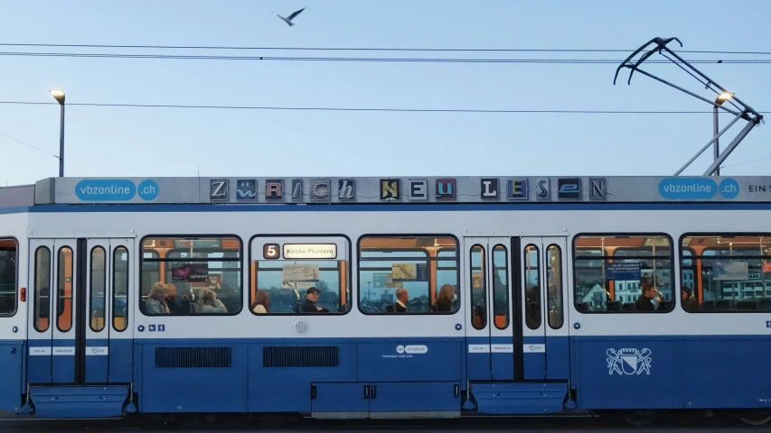a white blue and gray tram and a light pole
