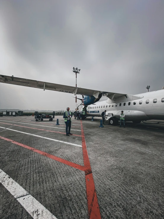 a couple of people stand next to an airplane on the tarmac