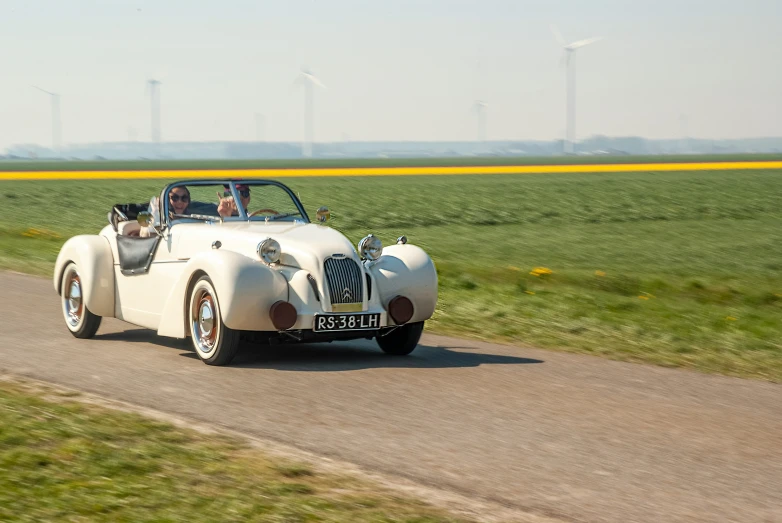 a vintage convertible driving down a dirt road