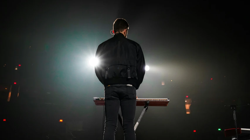 a man is standing at the piano in the spotlight