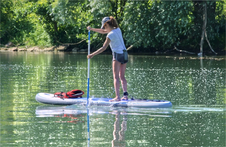 a young lady stands on a paddle board and uses it