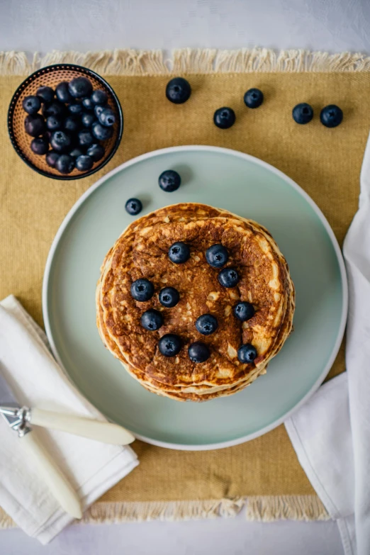 a stack of pancakes on a plate with blueberries