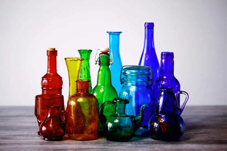 many colored glass vases on a table next to each other