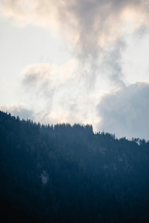 a large plane is flying in the sky above a hill with a few trees