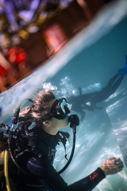 a woman in scuba gear with a large fish swimming behind her