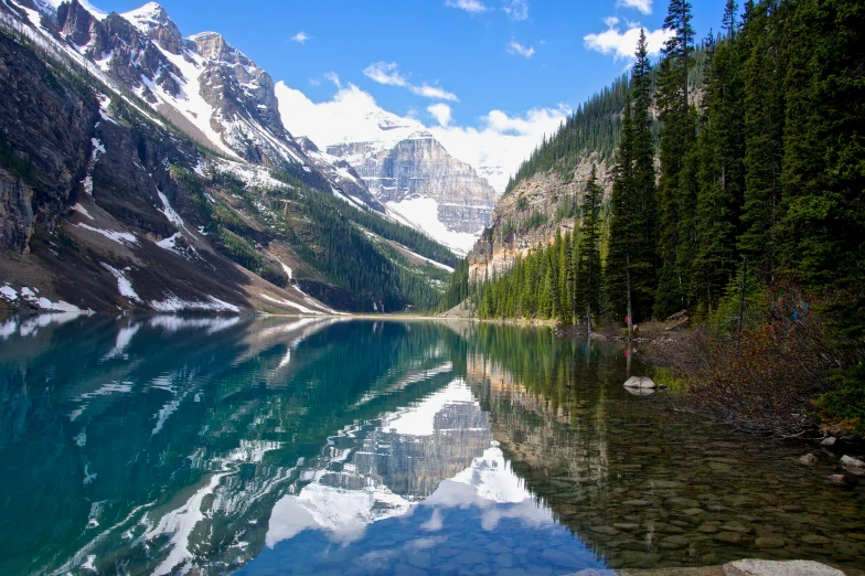 a lake surrounded by lush green trees and snow