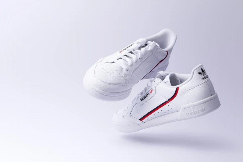 a pair of white tennis shoes with red stripes