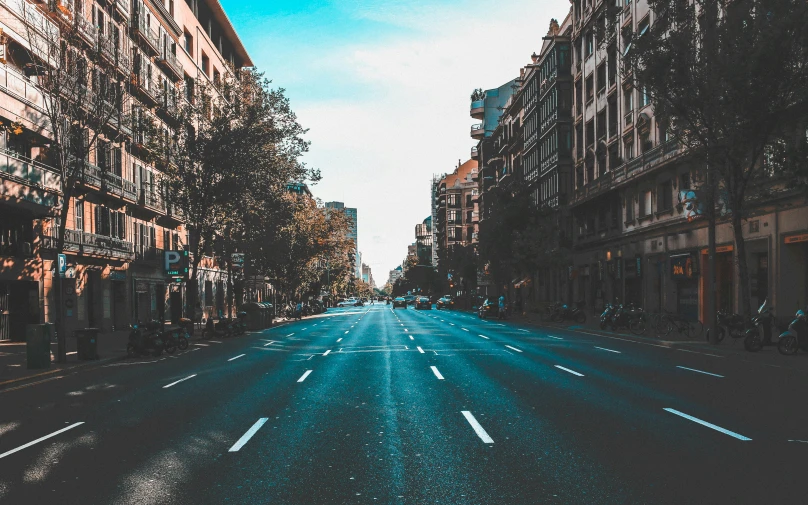 a street with buildings lined up and some cars going down it