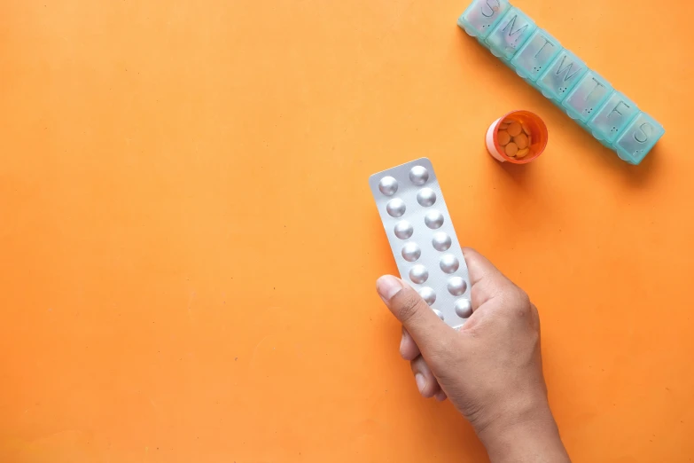 a person is holding a pill bottle and pills