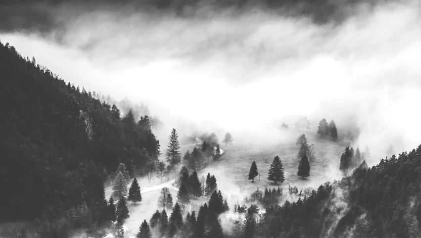 black and white pograph of foggy mountains on a cloudy day