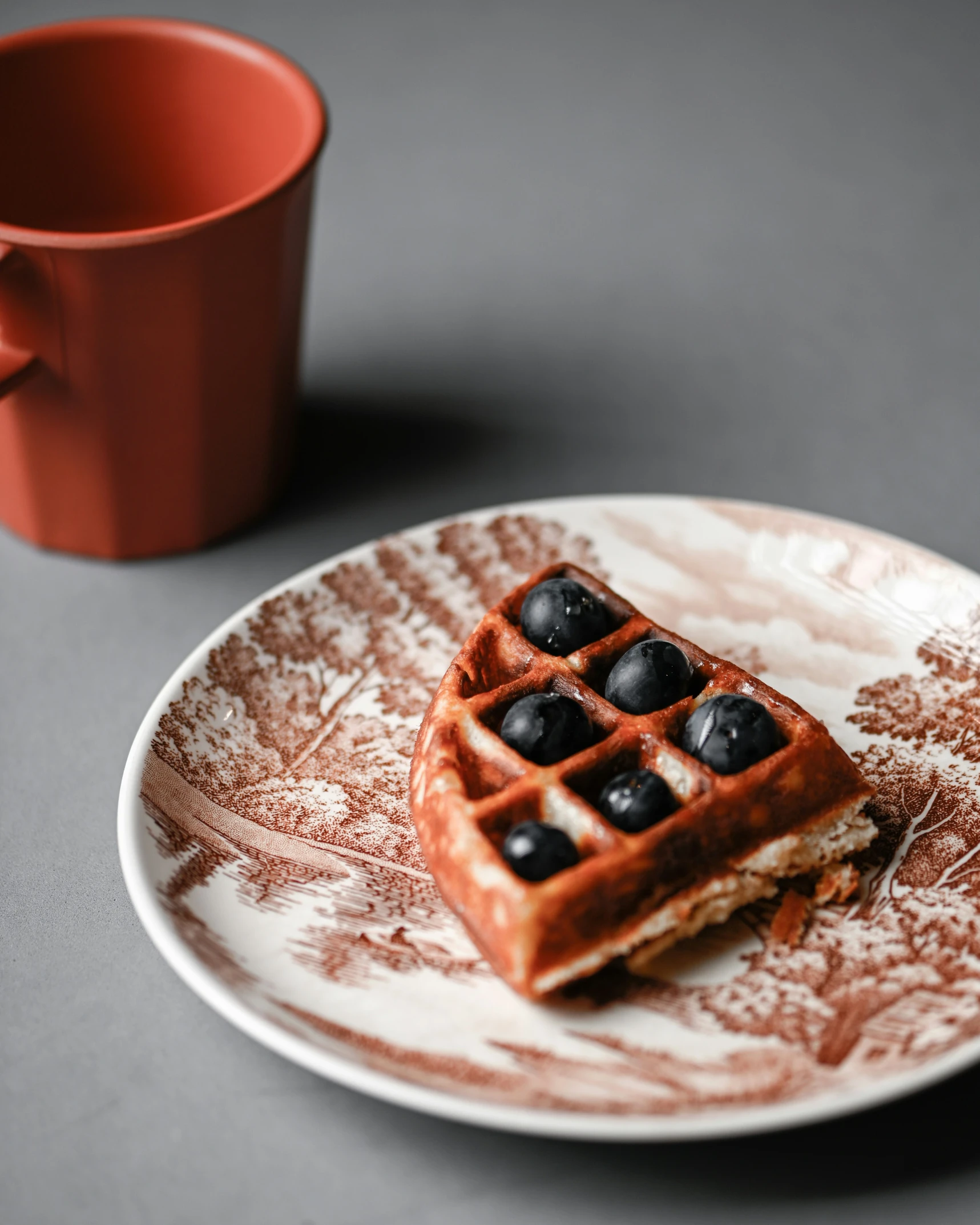 a chocolate waffle on a plate next to a cup