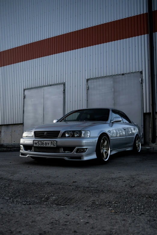 the silver car is parked by a wall in the parking lot