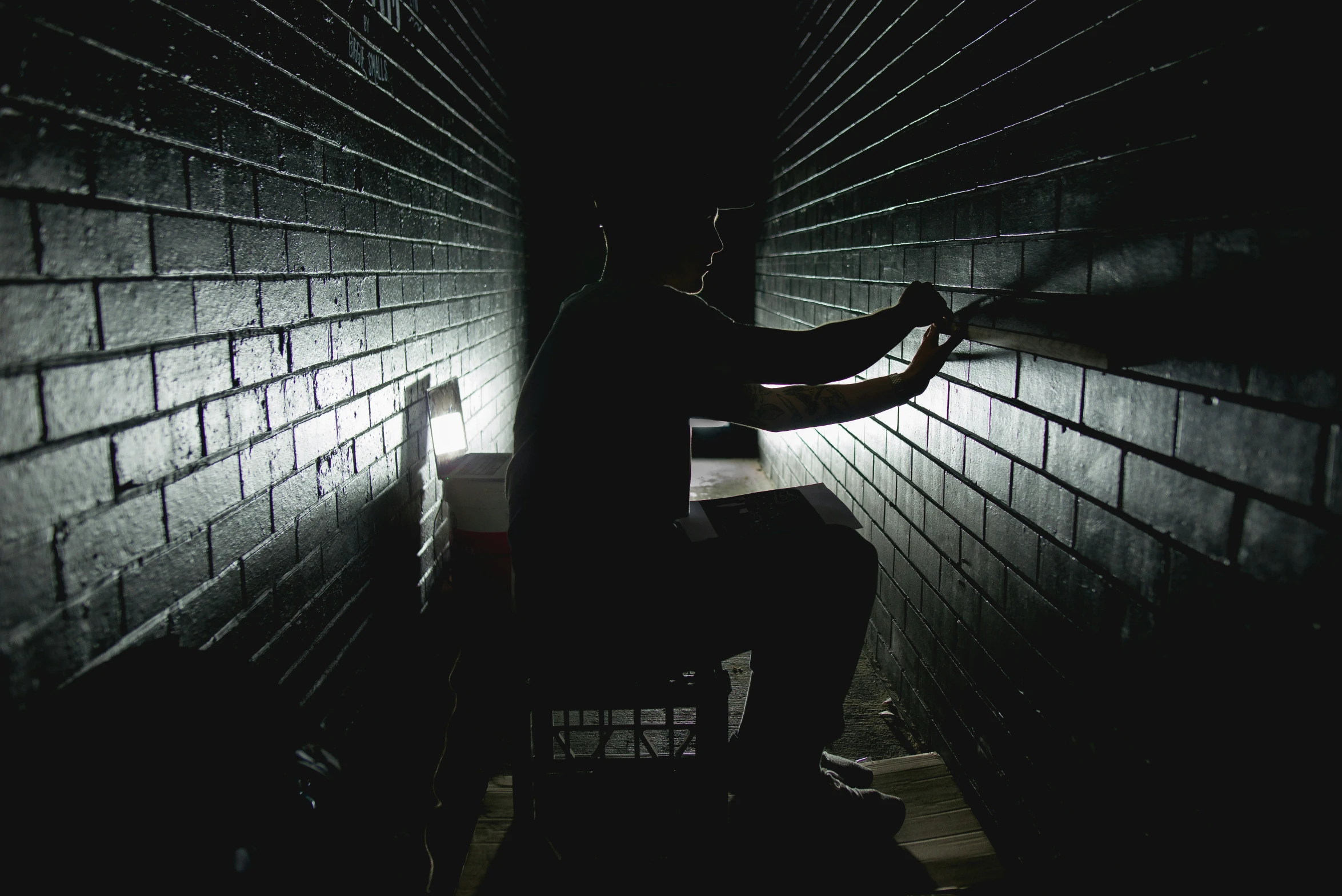 person sitting alone in a dark room with his arm outstretched up