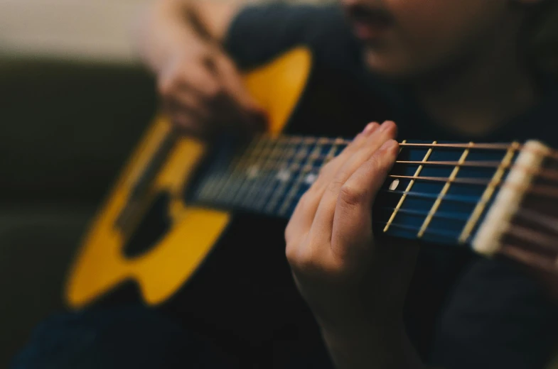 a person holding an acoustic guitar and playing a song