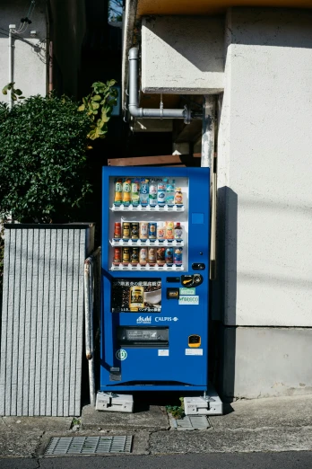 a blue vending machine sitting next to a building