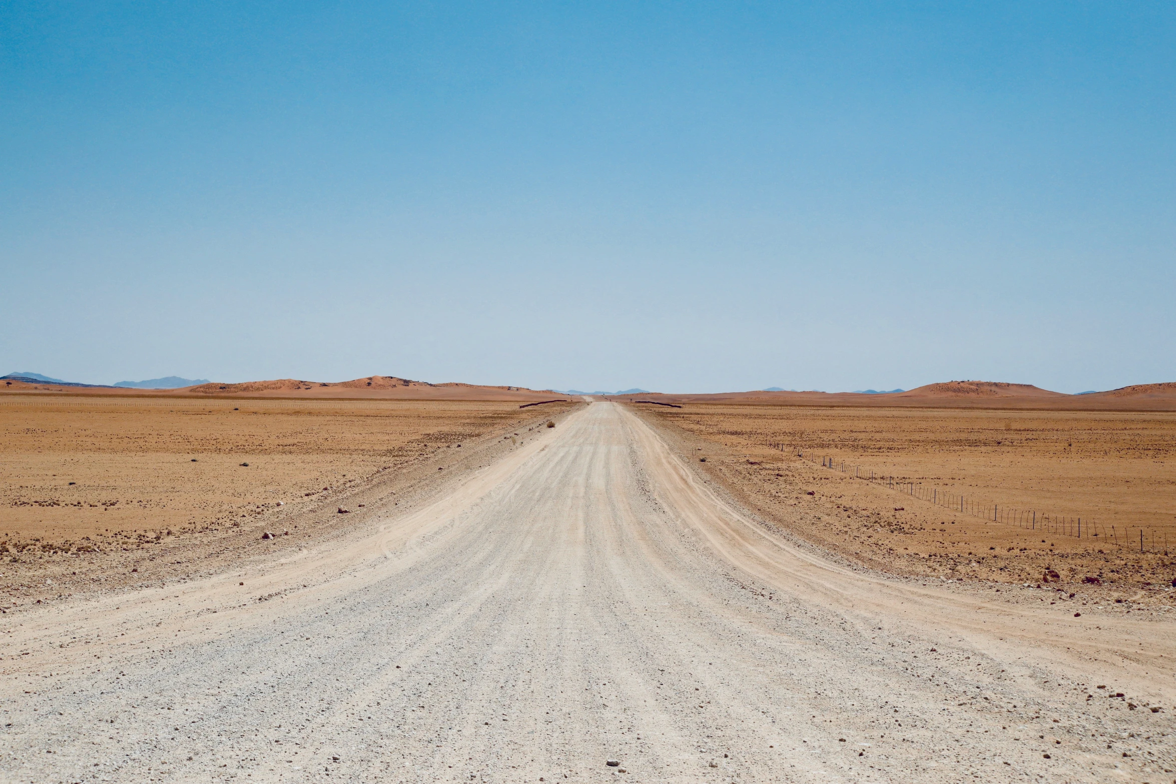 a dirt road and mountains in the desert