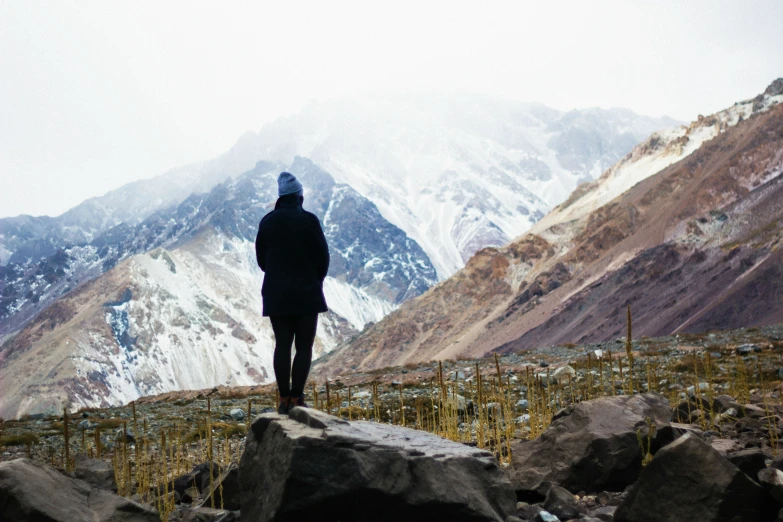 man on a cliff with mountains in the background