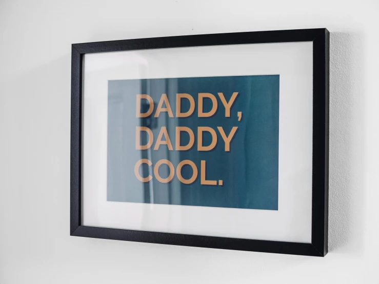 a framed poster sitting on a wall reading daddy, daddy, cool