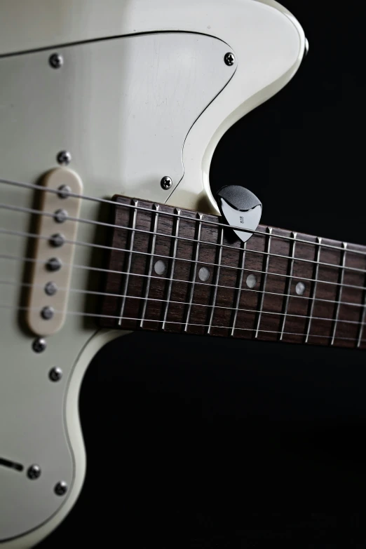 closeup of a white electric guitar's neck with the fret cap cover closed