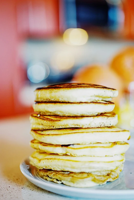 a stack of pancakes with oranges in the background
