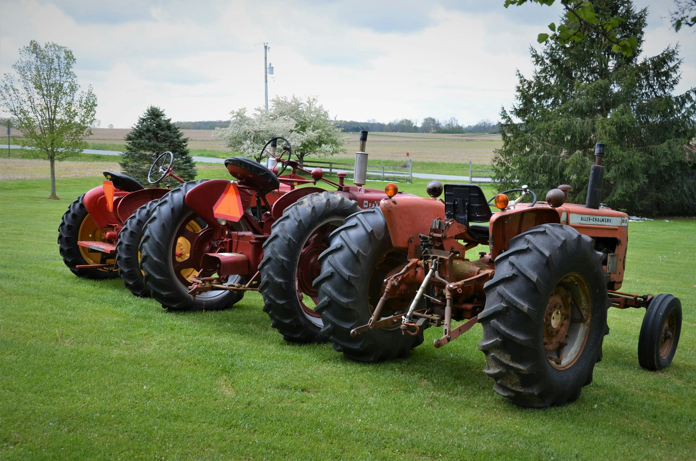 a row of vintage farmall tractors sitting on top of a lush green field