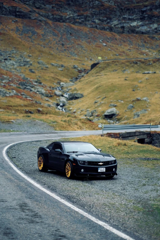 a black car parked on a curve by the side of a road