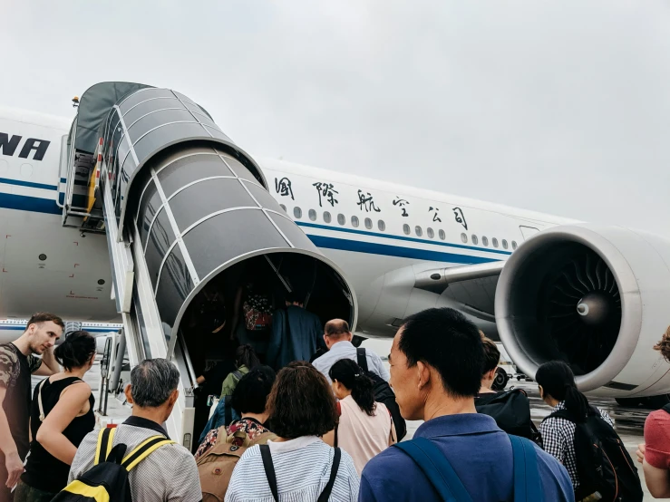 a group of people standing around an airplane at an airport