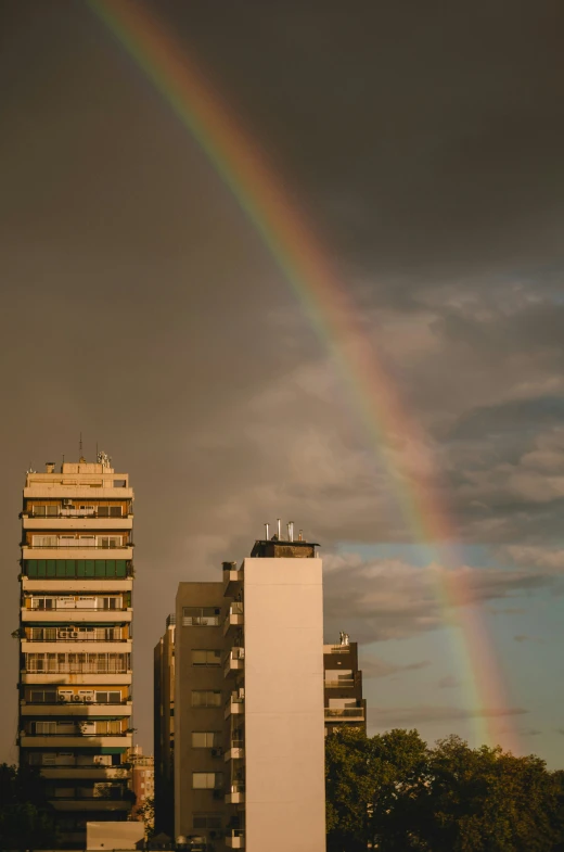 a rainbow appears in front of several buildings