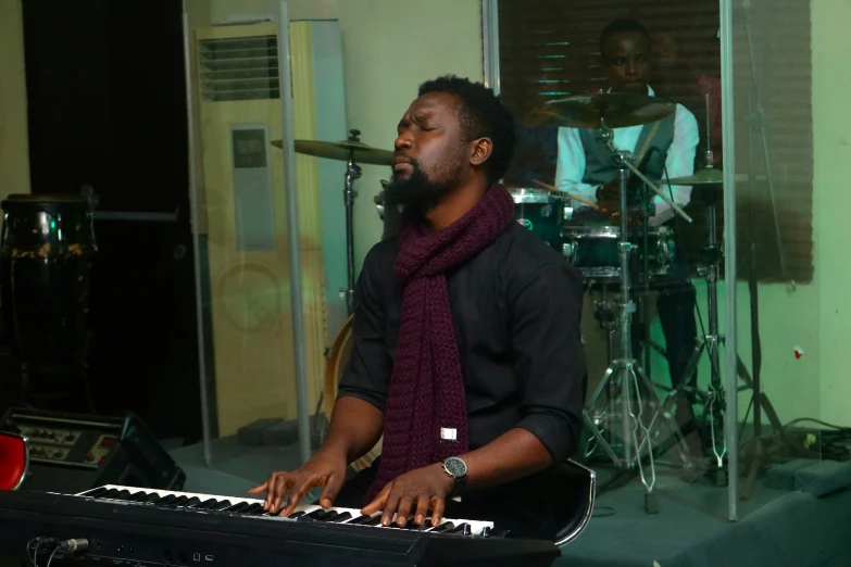 a man with a purple scarf standing in front of a keyboard