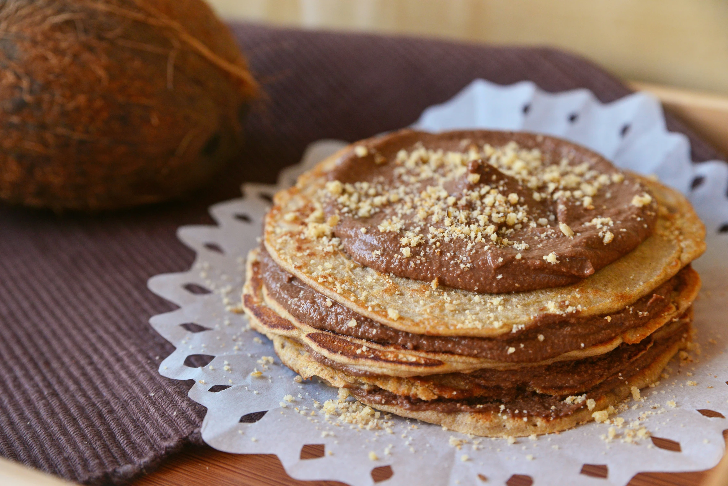 a stack of pancakes on a doily with a coconut