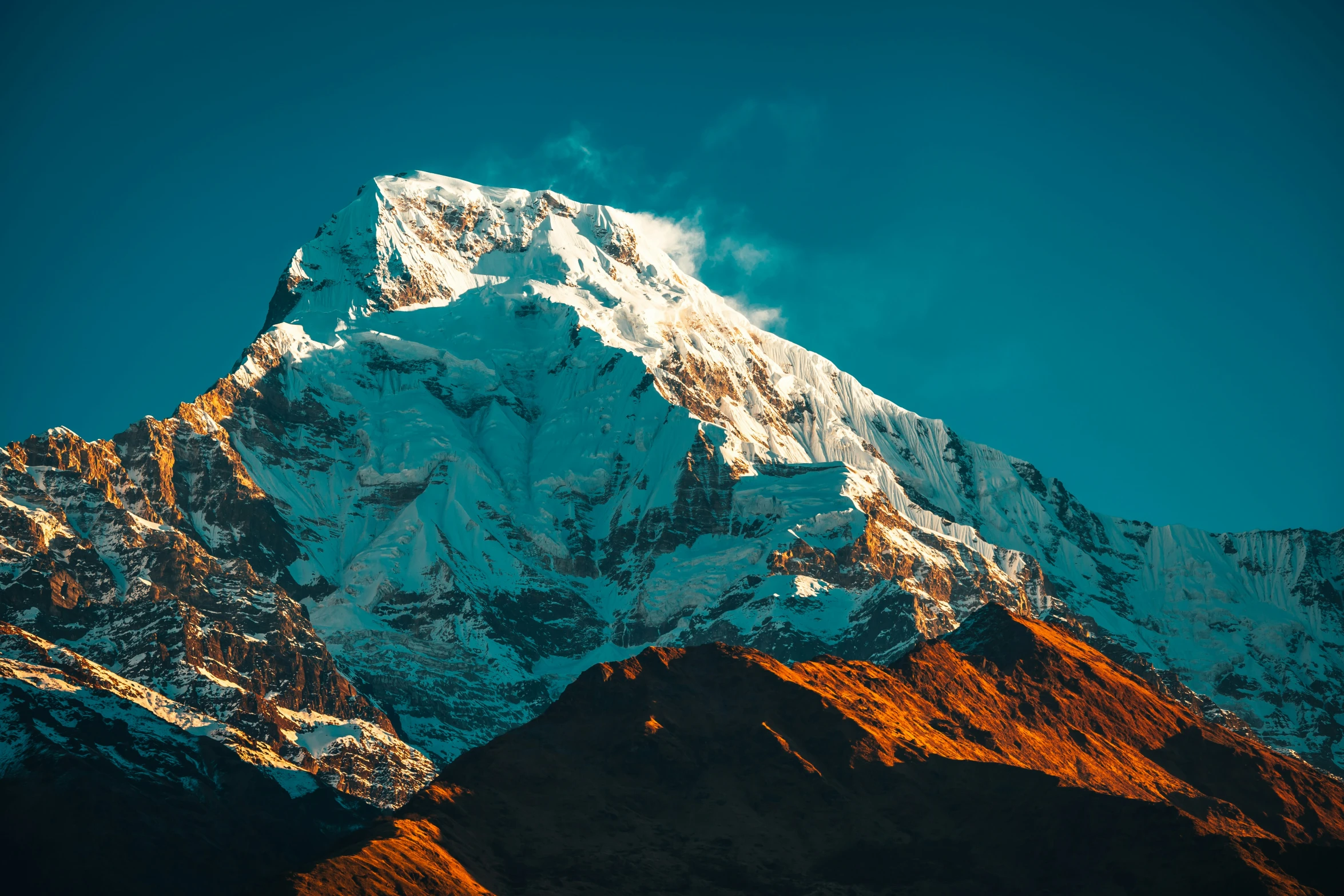 a large snow covered mountain rising above the sky