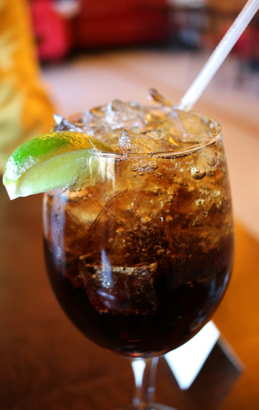 a glass of soda with an alcoholic garnish and some green leafy things in the background