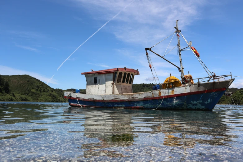 an old fishing boat is being hauled to shore by it's moorers