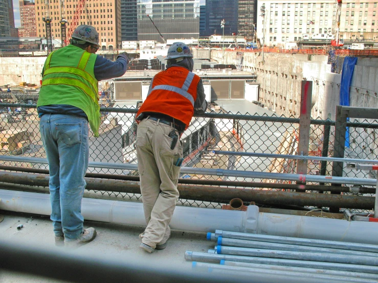 two men standing on a bridge wearing safety vests