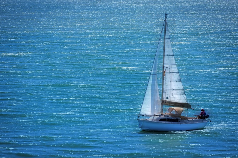 a small white boat on a big blue ocean
