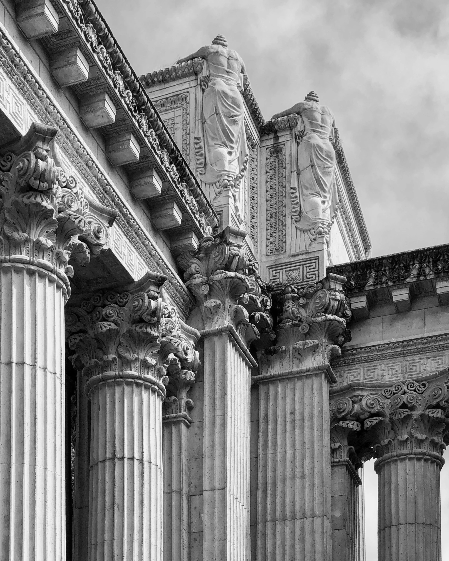 three columns with statues on them, under a cloudy sky