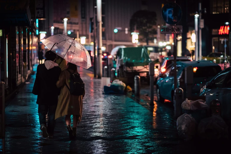 two people walking down a street with an umbrella in the dark