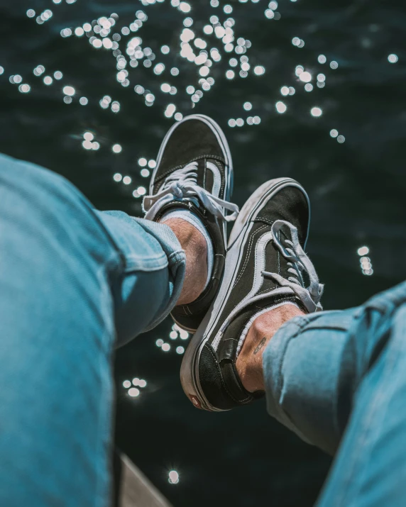 someone wearing sneakers standing on their feet and resting on the edge of a river