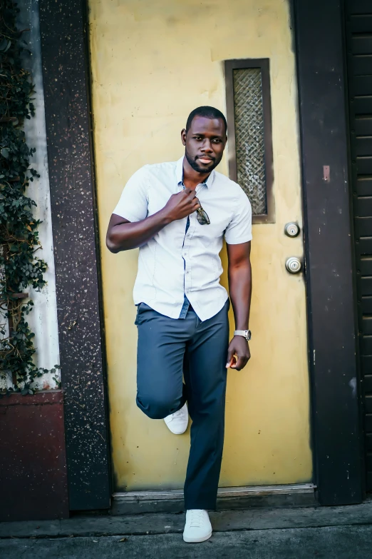 the man is posing in front of a yellow wall