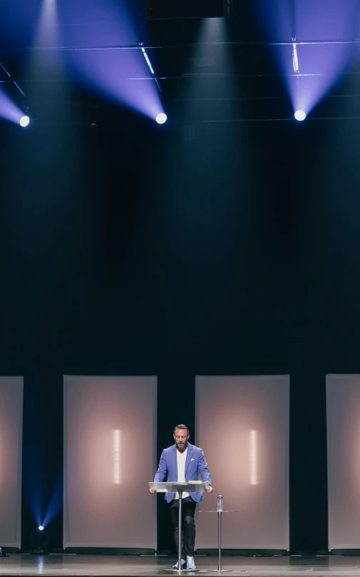 a man stands in front of a microphone while holding a projector