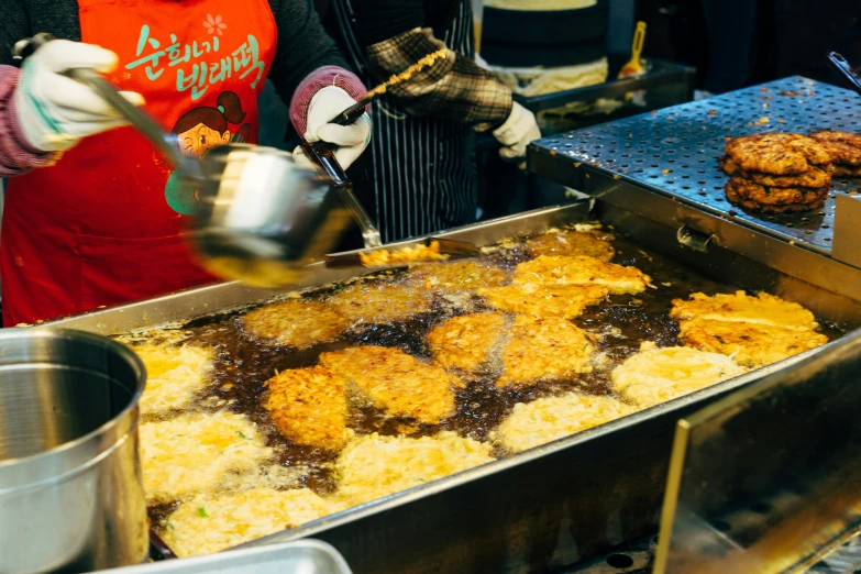 a large pan filled with food and a few other people standing by