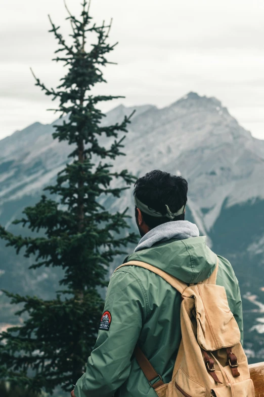 a man with a backpack looks at the mountains from above