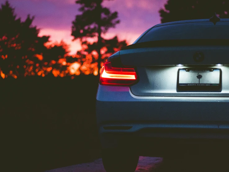 a white bmw is parked at night in a driveway