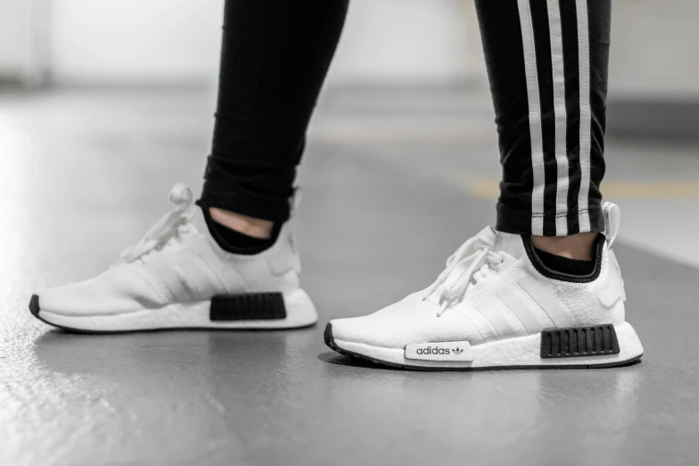 a person's legs in black pants and white sneakers