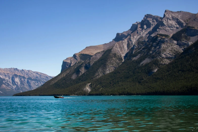 a boat floats on a mountain lake in front of the mountains