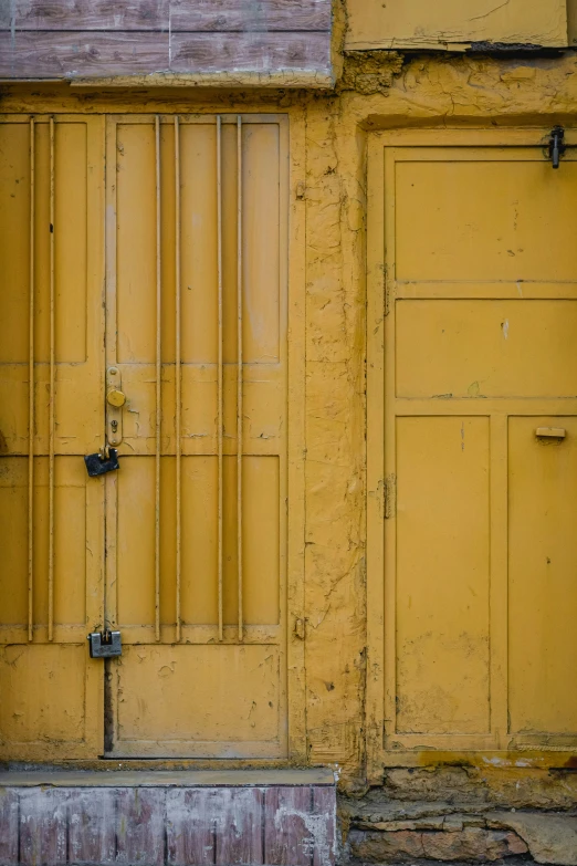 an old yellow building with wooden shutters and a cat outside