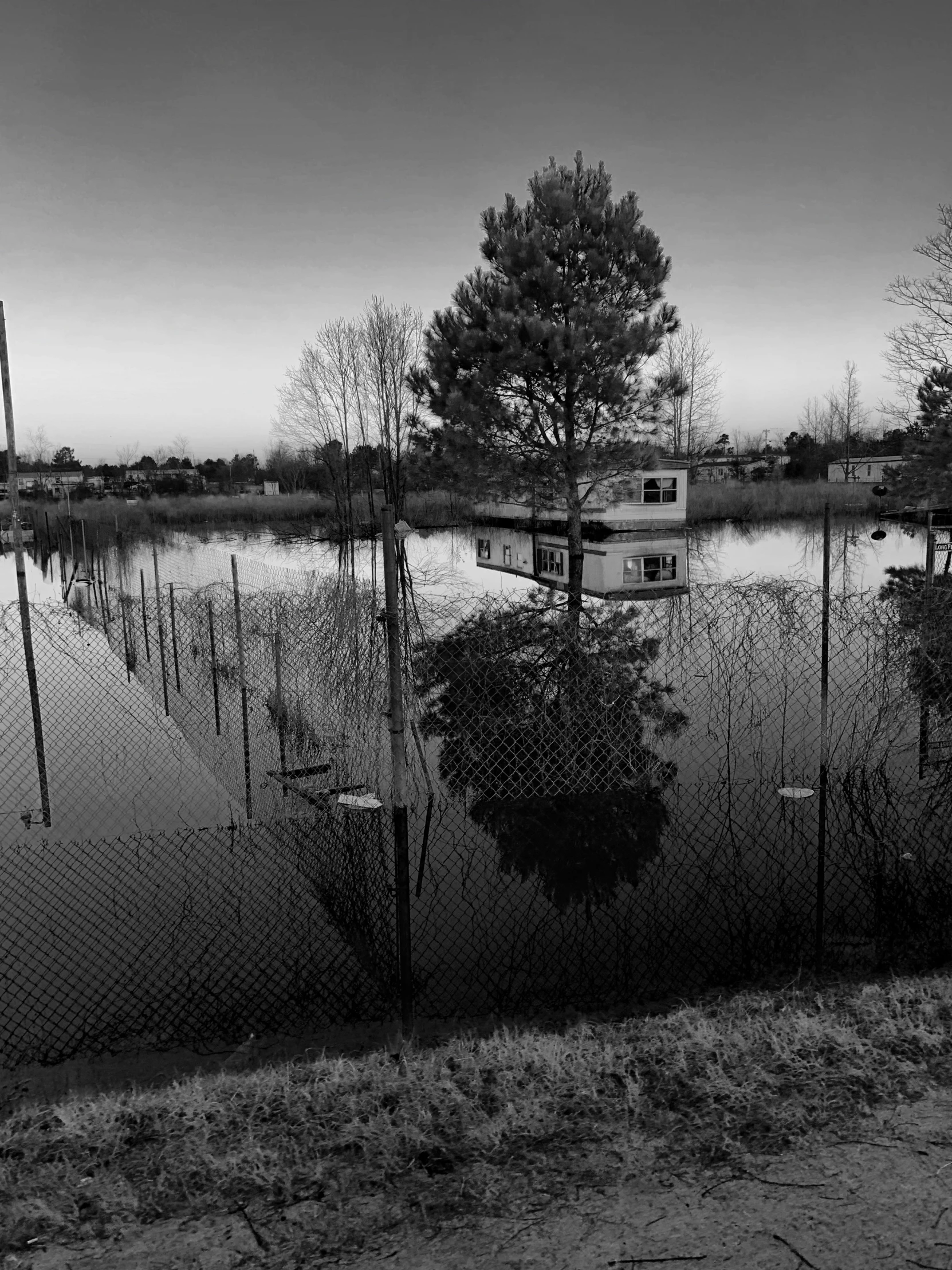 a black and white po of a house on a flooded road