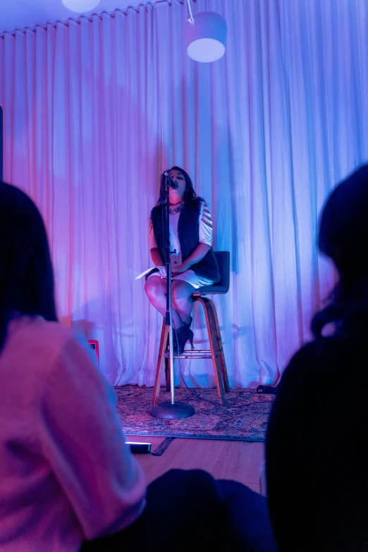 a girl sitting in a chair while a microphone is recording